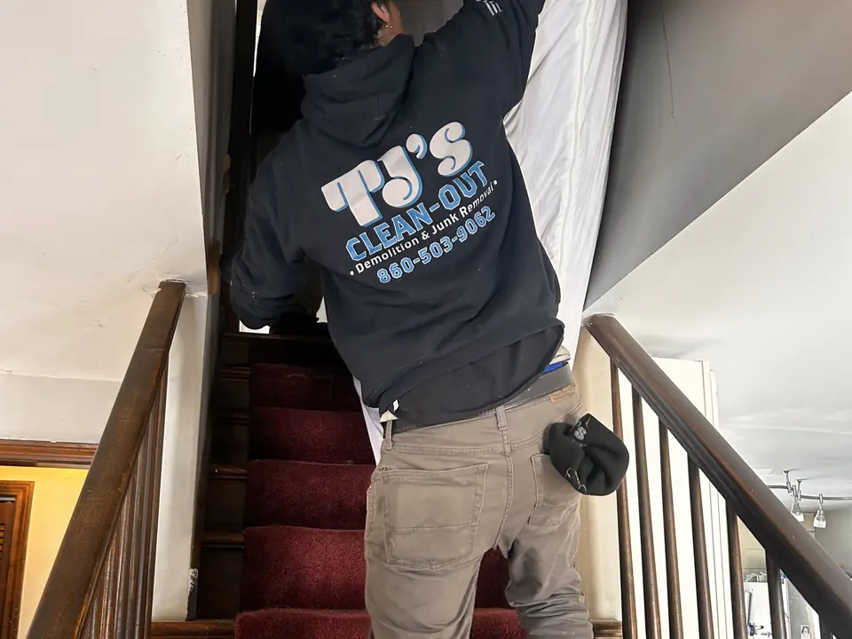 A TJ's crew member carrying items down a staircase